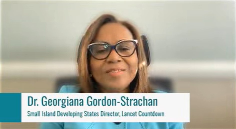 Nameplate showing “Dr. Georgiana Gordon-Strachan, Small Island Developing States Director, Lancet Countdown” on a teal and white banner in front of Georgina presenting.